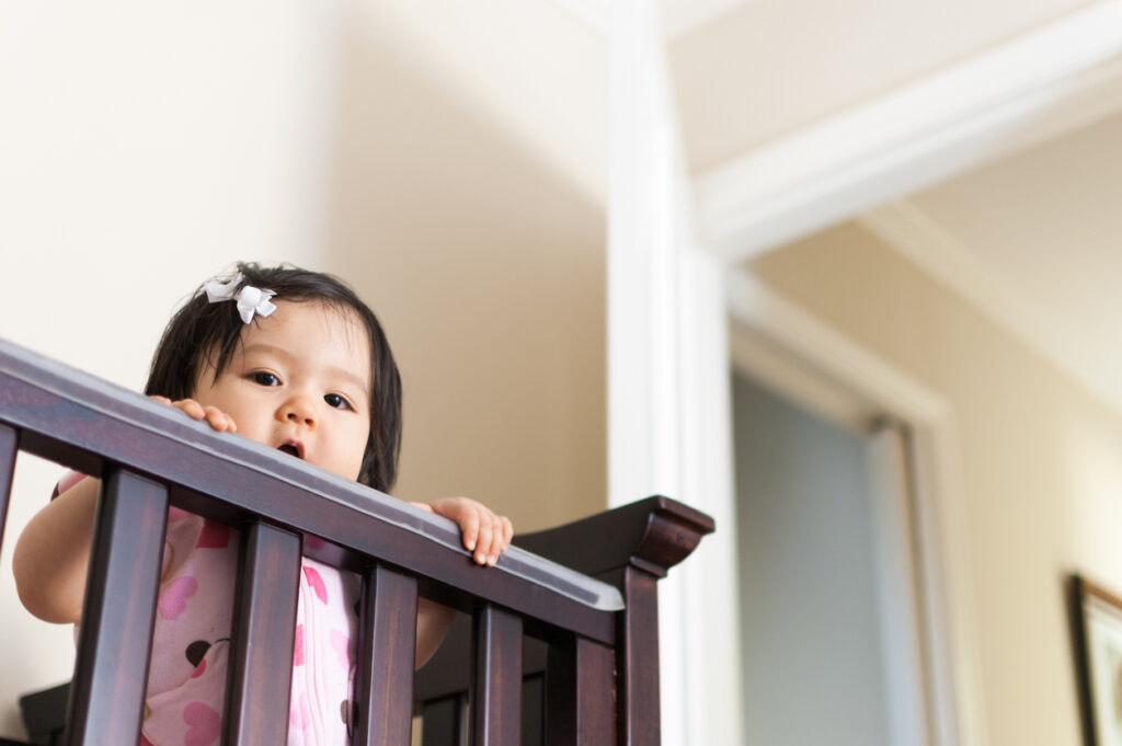 Cute Baby Asian girl peering out from her crib