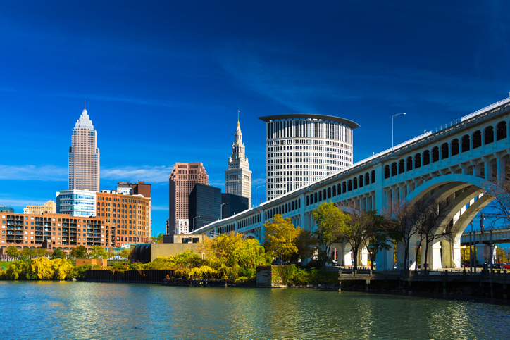 Downtown Cleveland skyline (featuring Key Tower) with the Cuyahoga River, Detroit-Superior Bridge, Autumn colored trees, and a deep blue sky with wispy clouds. Wide Angle.